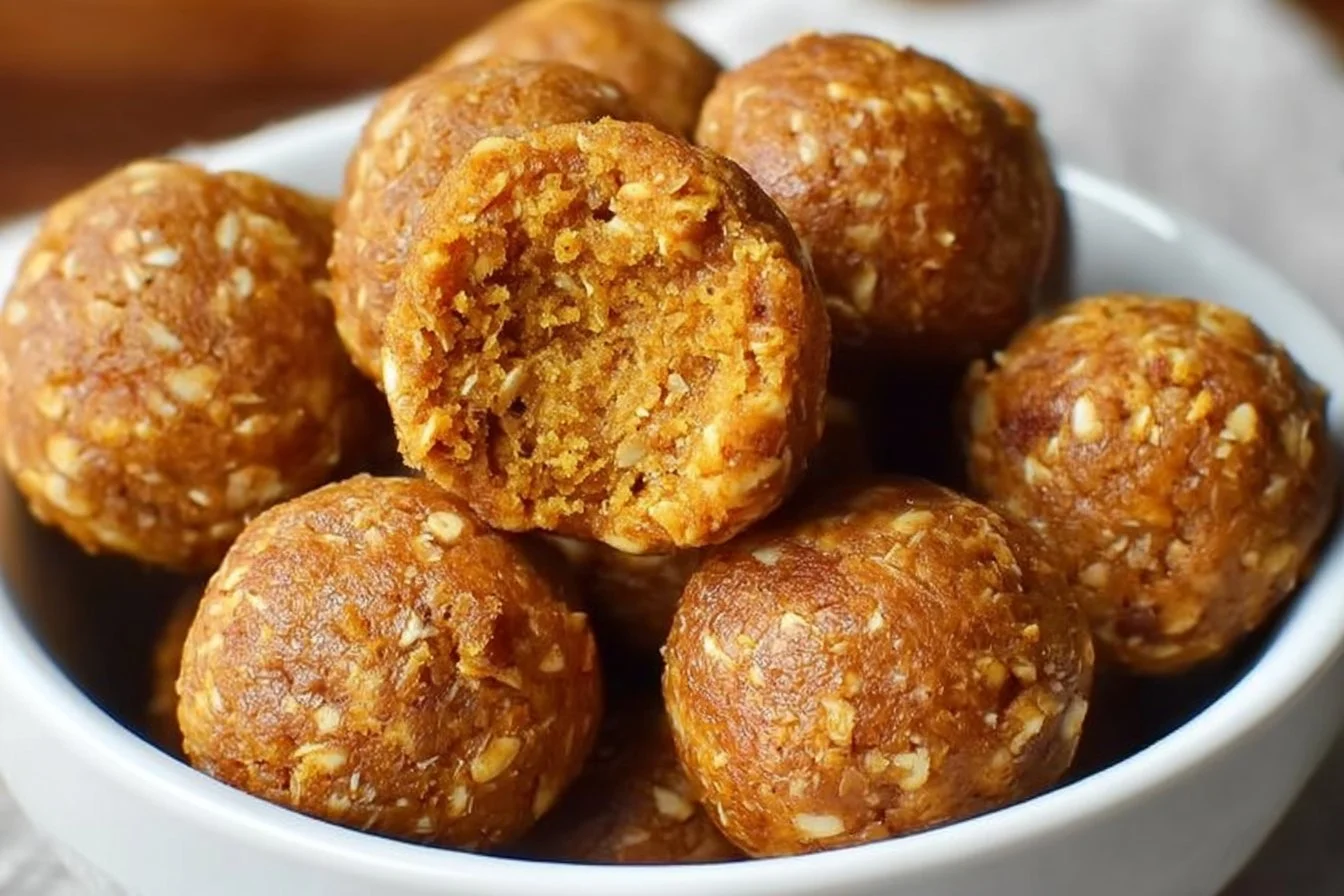 Homemade pumpkin protein balls on a wooden table with a sprinkle of cinnamon.