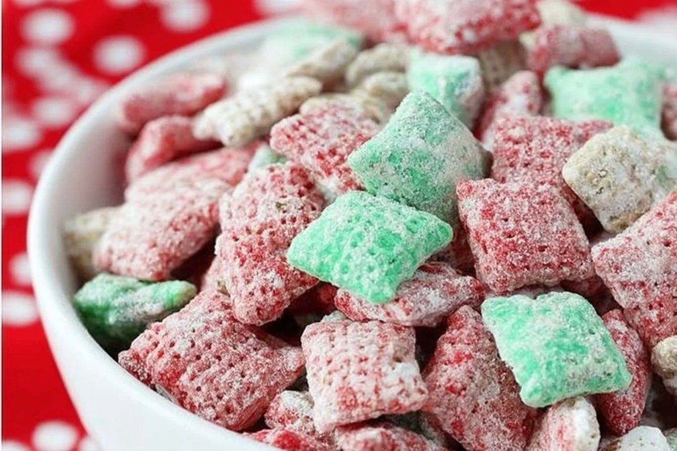 Bowl of Christmas Muddy Buddies with festive sprinkles and holiday decor