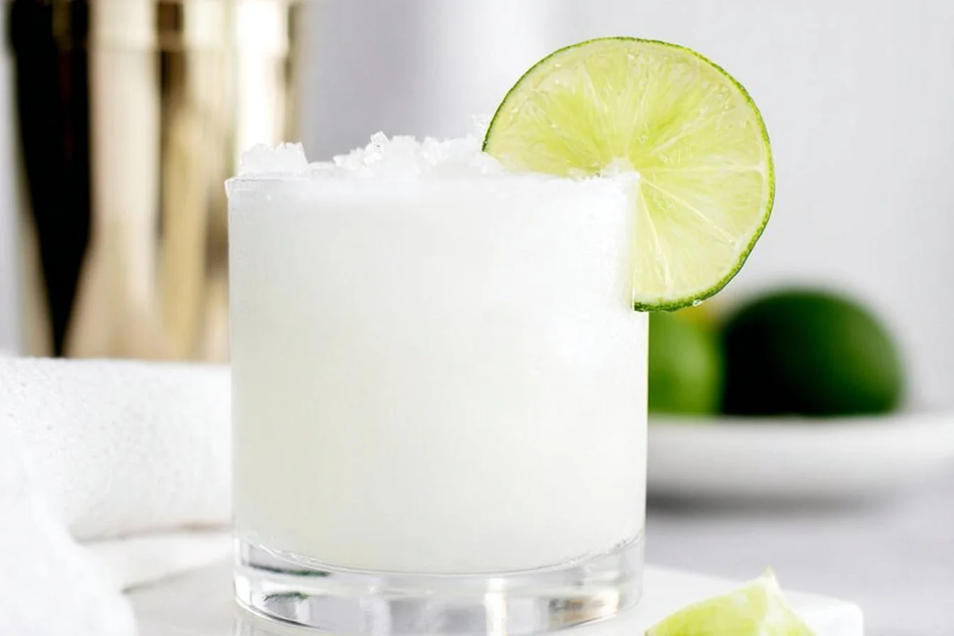 Refreshing coconut margarita served in a cocktail glass with lime garnish.