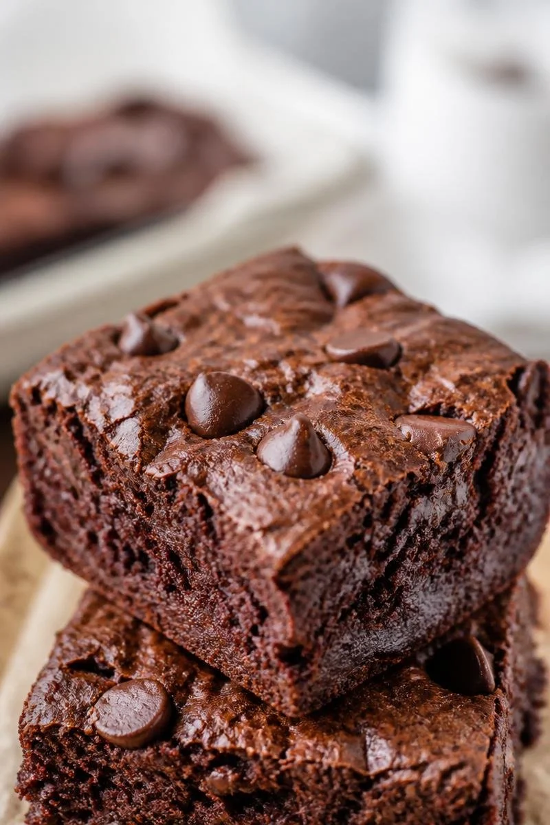 Fudgy Greek yogurt brownies on a white plate with chocolate drizzle